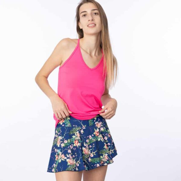Woman wearing a v-neck pink tank top and navy blue floral wrap flair skirt.